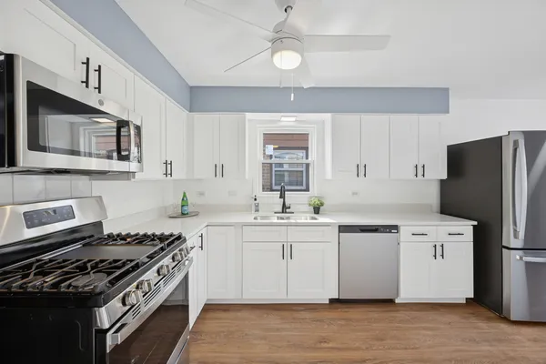 a kitchen with stainless steel appliances a sink a stove a refrigerator cabinets and a window