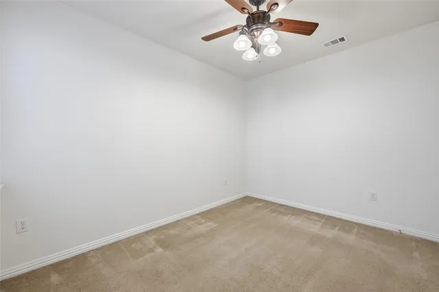 an empty room with a chandelier fan and view of a fan