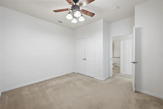 an empty room with a chandelier fan and windows