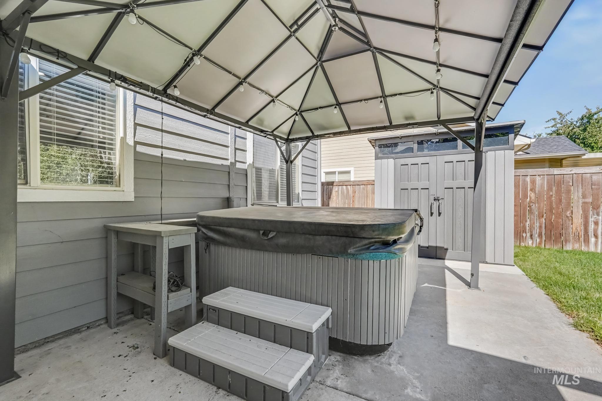 14421 West Stockwell Street Boise, ID 83713 - Photo 18 of 20 Outdoor hot tub area featuring a metal gazebo with string lighting, concrete patio, and a storage shed with double doors