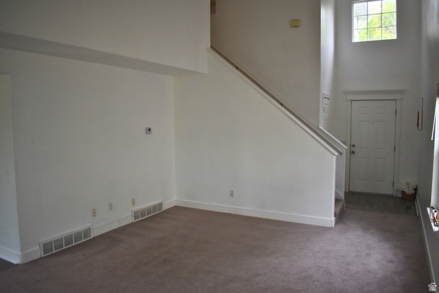 3327 East Windhover Road Eagle Mountain, UT 84005 - Photo 6 of 38 Two-story foyer with high ceilings, featuring a multi-pane window, staircase with a handrail, and a paneled entry door
