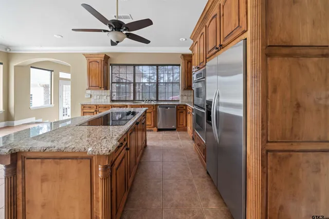 a kitchen with stainless steel appliances granite countertop a refrigerator a sink a stove and island