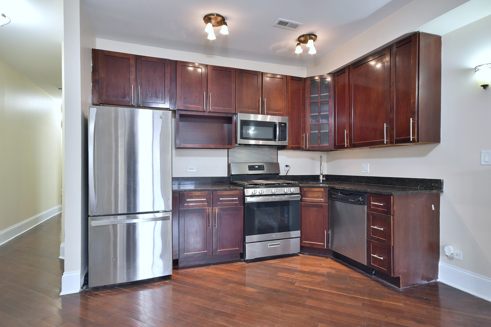 4819 South Prairie Avenue, Unit 1 Chicago, IL 60615 - Photo 3 of 16 a kitchen with granite countertop wooden floors stainless steel appliances and a sink