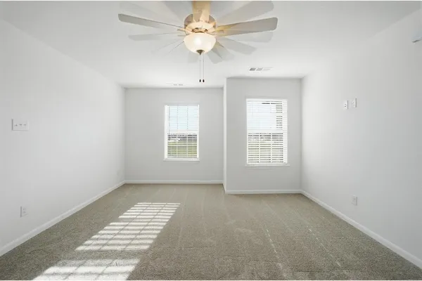 an empty room with windows and ceiling fan