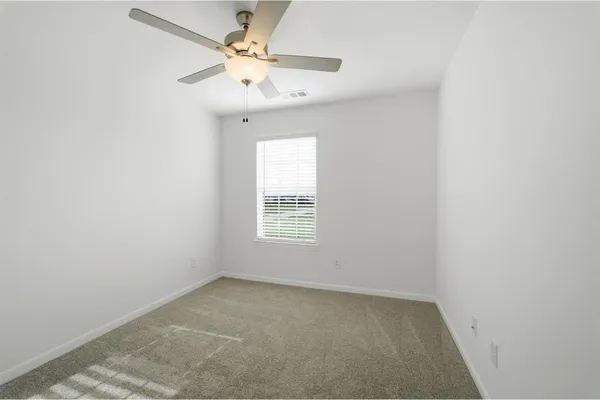 an empty room with a window and a fan
