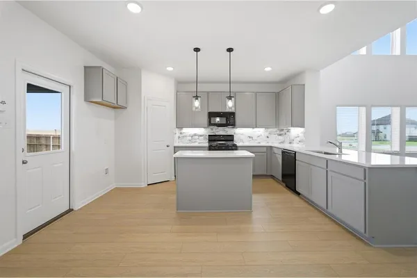 a large kitchen with stainless steel appliances kitchen island a large counter top a sink a stove a refrigerator and cabinets