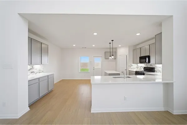 a large white kitchen with a sink and dishwasher a stove top oven with wooden floor