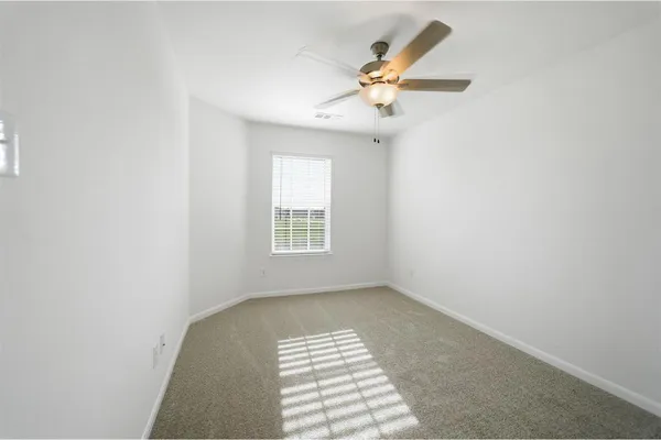 an empty room with windows and fan