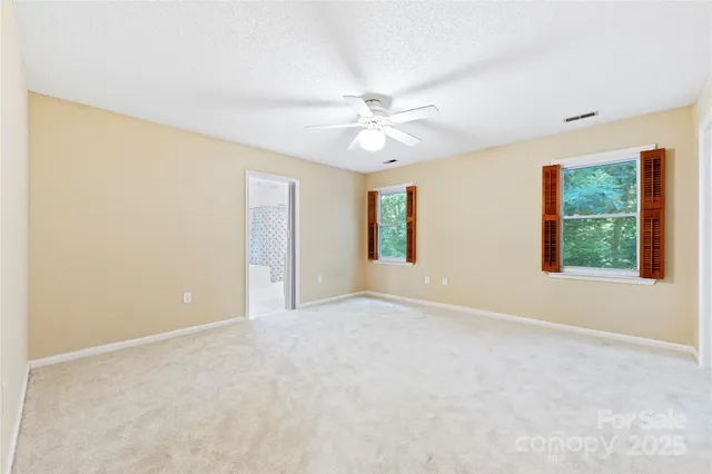 an empty room with windows and fan