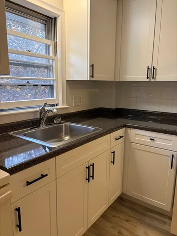 a kitchen with granite countertop white cabinets white appliances and a sink