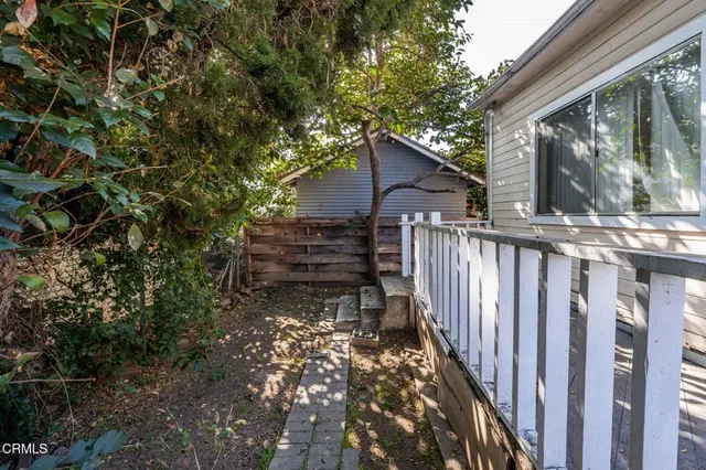 a view of a house with wooden fence and a tree