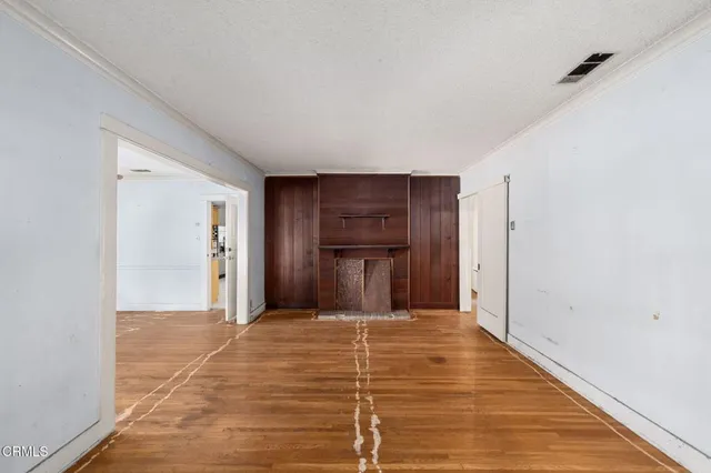a view of a livingroom with wooden floor and kitchen