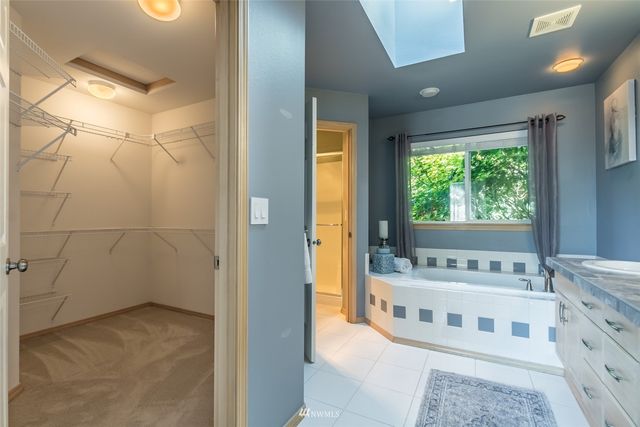 a spacious bathroom with a double vanity sink a large mirror and a bathtub next to a window