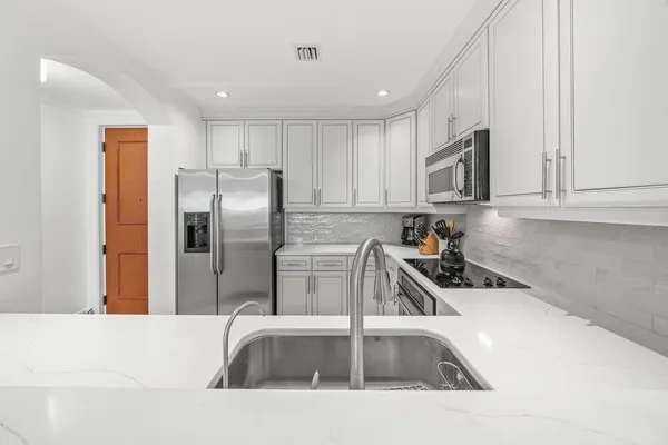 a kitchen with stainless steel appliances granite countertop a sink a microwave a refrigerator and white cabinets