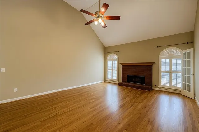 a view of an empty room with wooden floor fireplace and a window