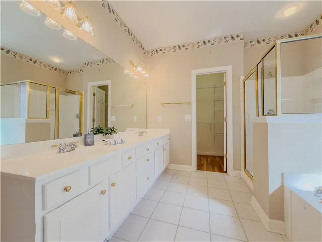 a spacious bathroom with a double vanity sink a mirror and a shower