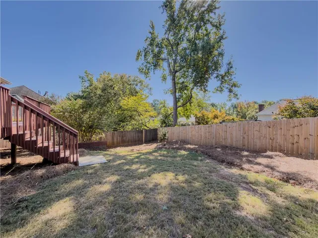 a view of backyard with wooden fence and trees