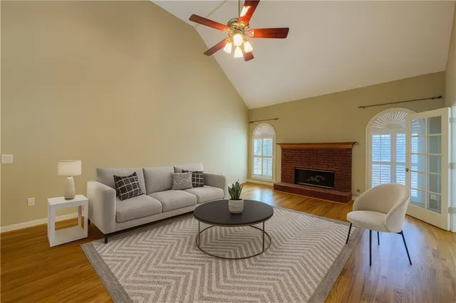 an empty room with wooden floor a chandelier fan a fireplace and windows