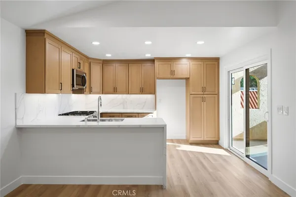 a view of kitchen with stainless steel appliances granite countertop a refrigerator a sink and a stove with wooden floor