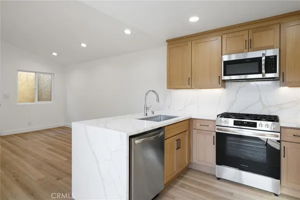 a kitchen with stainless steel appliances a stove microwave and sink