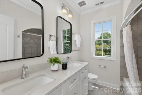 a bathroom with a granite countertop sink a toilet a mirror and a window