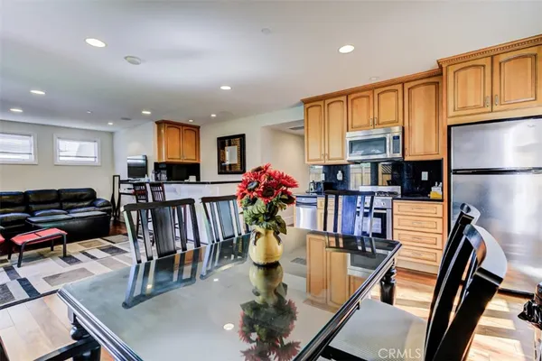 a kitchen with stainless steel appliances granite countertop a refrigerator a sink dishwasher a dining table and chairs with wooden floor