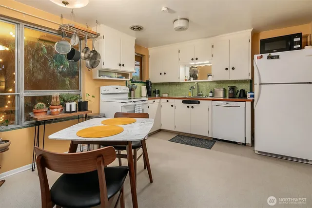 a kitchen with stainless steel appliances a table chairs and a refrigerator