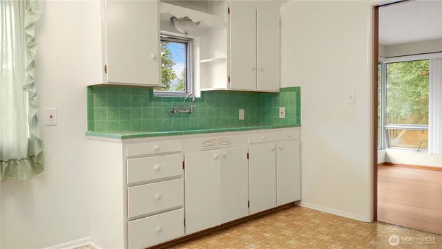 a view of a kitchen with refrigerator and white cabinets