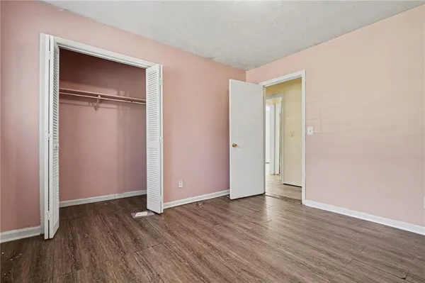 an empty room with wooden floor & closet area