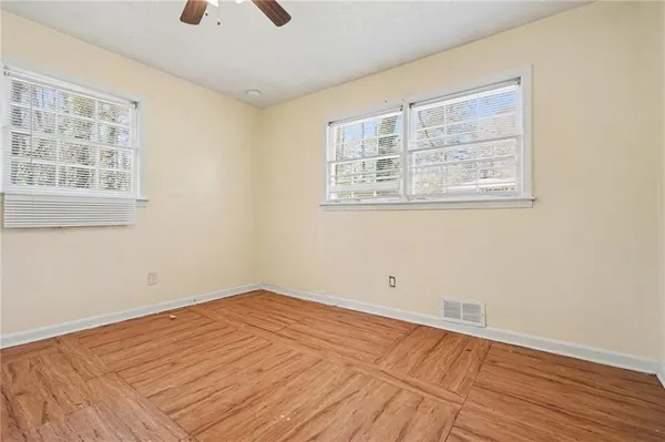 a view of empty room with wooden floor and fan