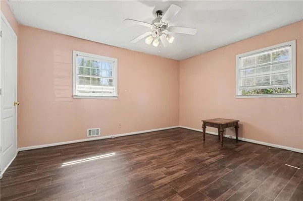 a view of an empty room with window and wooden floor