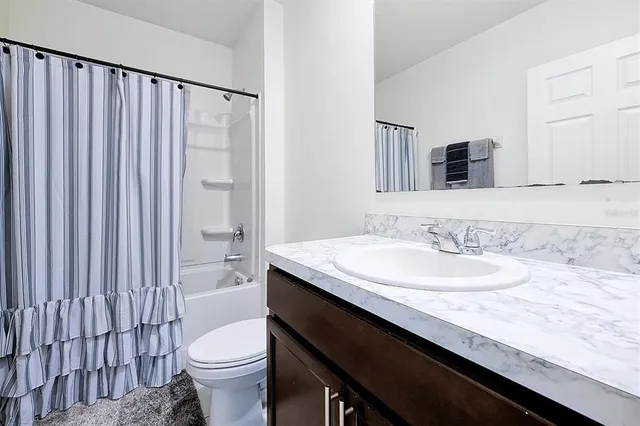 a bathroom with a granite countertop sink a toilet a mirror and shower