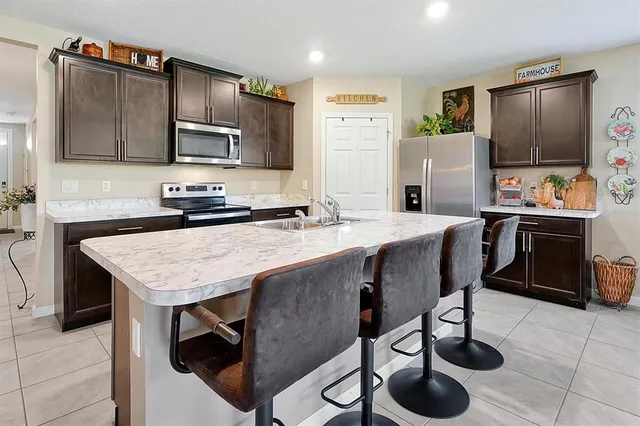 a kitchen with stainless steel appliances kitchen island granite countertop a stove a sink a microwave and wooden cabinets