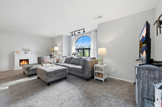 1175 Canyon Road, Unit 86 Ogden, UT 84404 - Photo 7 of 29 Carpeted living space featuring an arched window, white trim, and a decorative fireplace