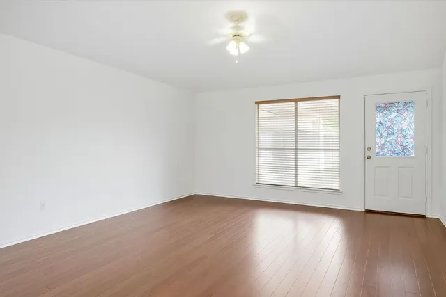 an empty room with wooden floor and windows