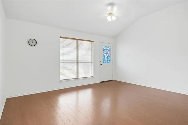 an empty room with wooden floor and windows