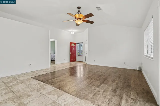 an empty room with ceiling fan and window