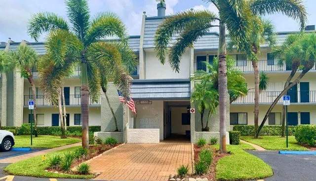 front view of house with a yard and palm trees