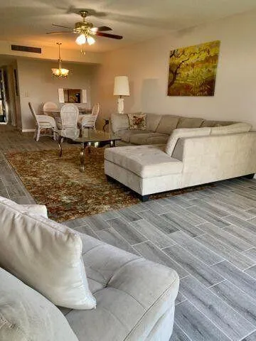 a living room with couches and kitchen view with wooden floor