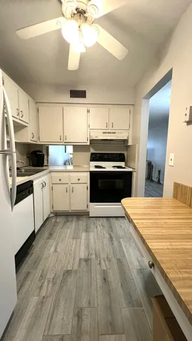 a kitchen with stainless steel appliances granite countertop a stove top oven a sink dishwasher and a refrigerator with wooden floor