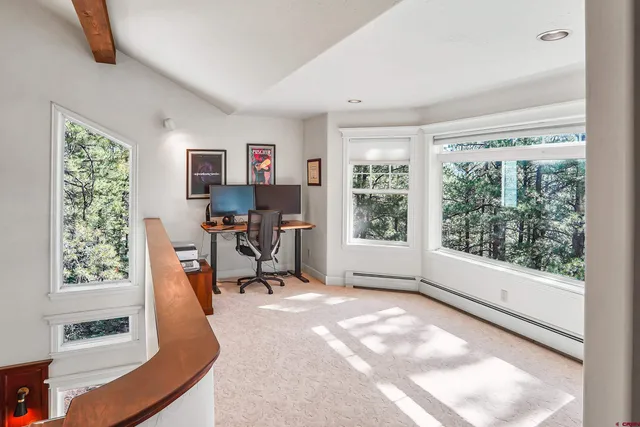a view of a hallway to a room with wooden floor and windows