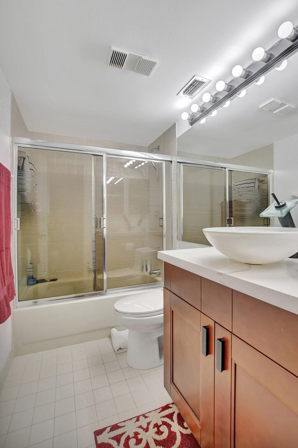 7194 Promenade Drive, Unit 102 Boca Raton, FL 33433 - Photo 24 of 56 a bathroom with a double vanity sink toilet and shower