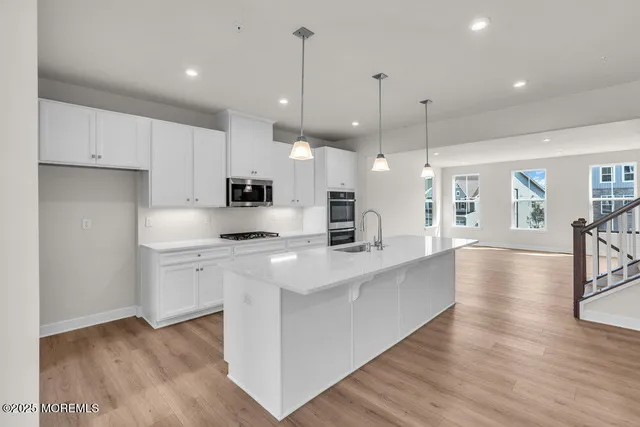 a large kitchen with stainless steel appliances kitchen island a large counter top and a wooden floors