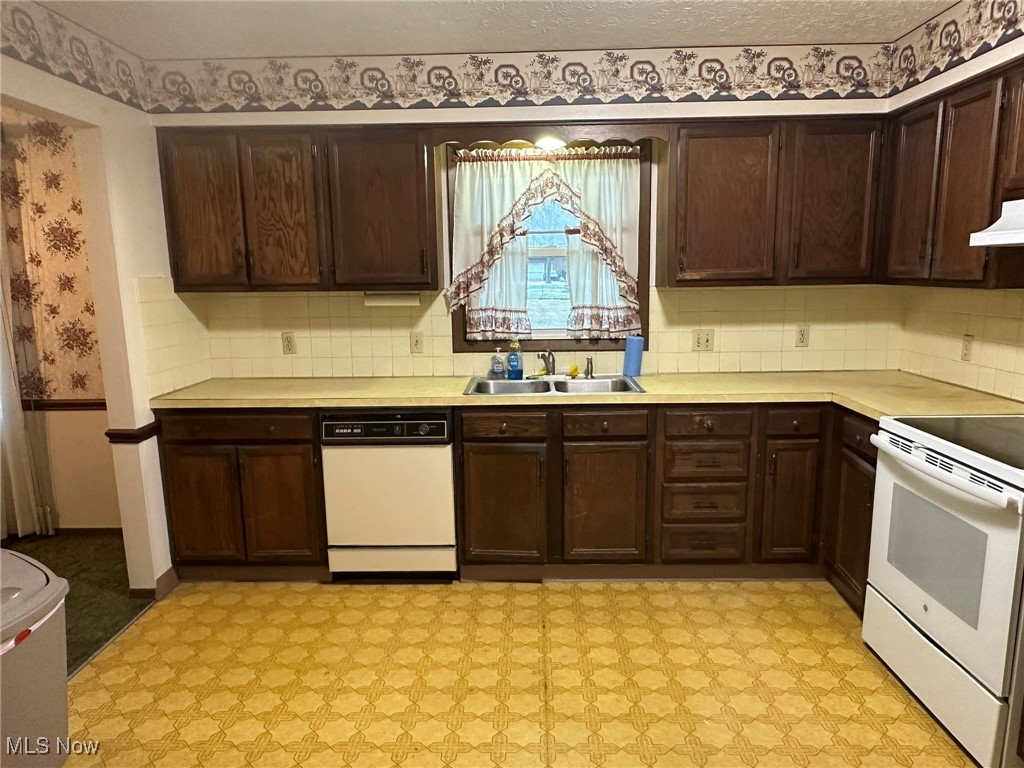 97 West Howe Road Tallmadge, OH 44278 - Photo 22 of 35 Kitchen featuring sink, white appliances, dark brown cabinetry, a textured ceiling, and decorative backsplash