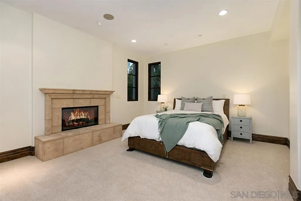 7620 Iluminado San Diego, CA 92127 - Photo 17 of 25 a spacious bedroom with a bed and a fireplace
