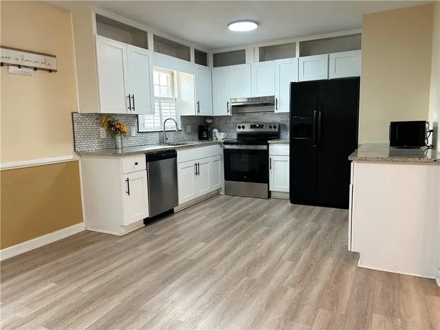 a kitchen with a refrigerator a stove top oven a sink and dishwasher with wooden floor