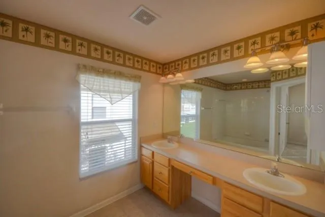a bathroom with double vanity and a mirror