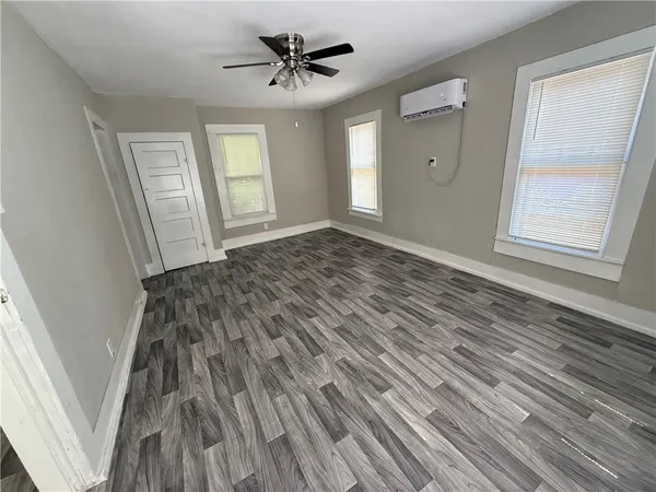 a view of empty room with wooden floor and fan