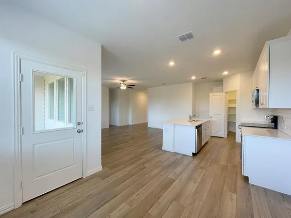 a open kitchen with white cabinets wooden floor and stainless steel appliances
