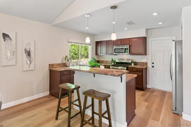 a kitchen with stainless steel appliances granite countertop a table chairs refrigerator and a sink